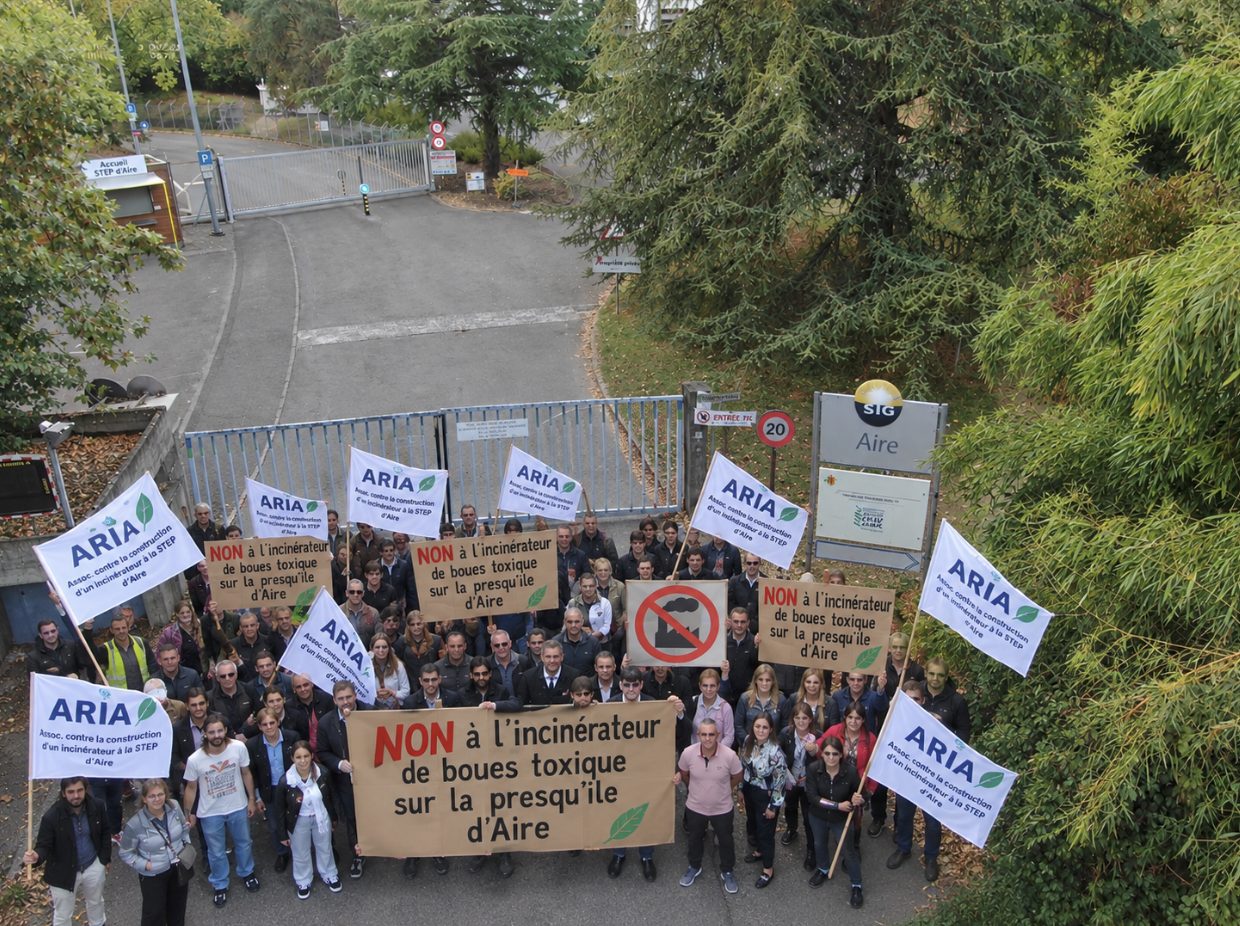 Rassemblement de riverains avec banderoles ARIA devant l’entrée de la STEP d’Aïre, vu du ciel